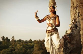 Cambodian dancer in traditional attire posing by ancient temple ruin outdoors