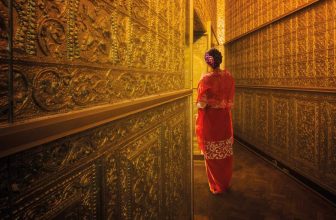 Woman in red traditional dress walking in a hallway with golden ornate walls