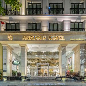Entrance of Anatole Hotel Hanoi illuminated at night with classical columns and statues