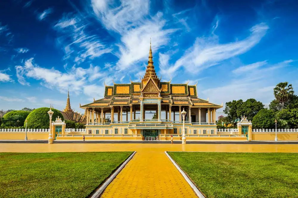 Golden traditional temple with spire, clear blue sky, and green gardens