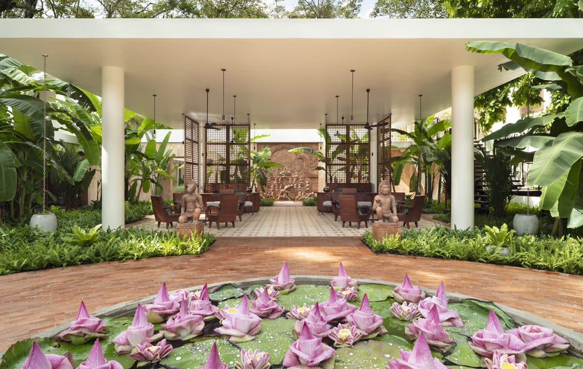 Open-air lobby seating area with lotus pond and tropical plants at FCC Angkor by Avani