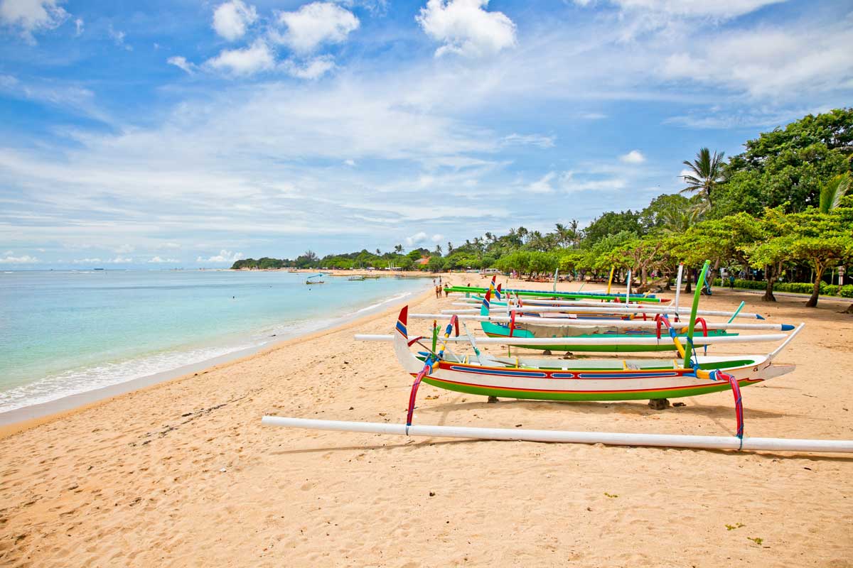 Colorful traditional Indonesian boats on sandy tropical beach near clear sea