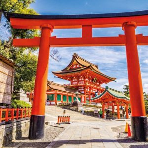 Red torii gate at entrance to traditional Japanese shrine with visitors