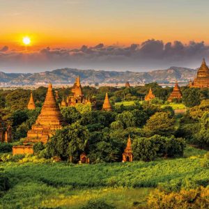 Sunset over ancient pagodas and green landscape with mountains and clouds in background