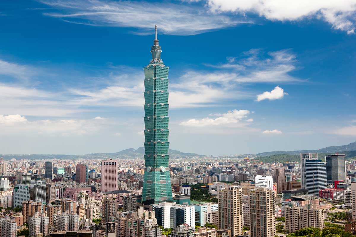 Taipei 101 skyscraper towering over Taipei cityscape under blue sky with clouds