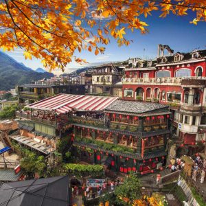 Colorful hillside village with traditional buildings and red lanterns under blue sky