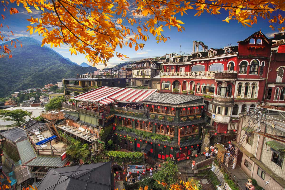 Colorful hillside village with traditional buildings and red lanterns under blue sky