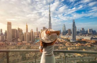 Woman in white dress and hat overlooking Dubai skyline with Burj Khalifa