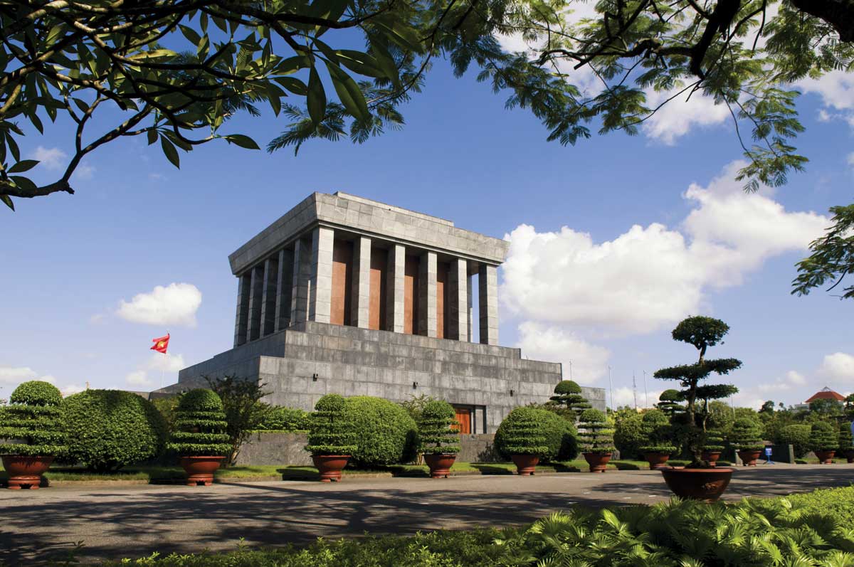 Ho Chi Minh Mausoleum with manicured trees and blue sky