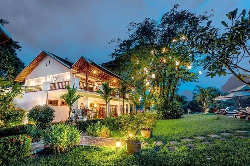 Riverside boutique resort garden lit up with lanterns and tropical plants at dusk