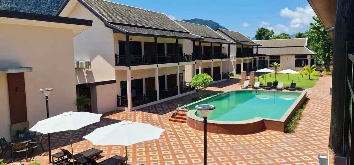 Boutique hotel courtyard with swimming pool, sun loungers, umbrellas, and mountain background