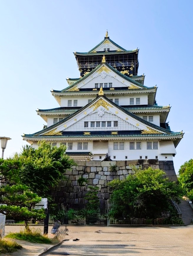 Osaka Castle with ornamental roof and stone base under clear blue sky