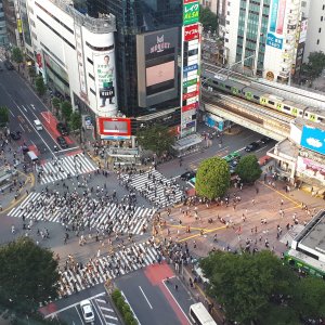 Aerial view of busy city scramble crossing with many pedestrians and train tracks