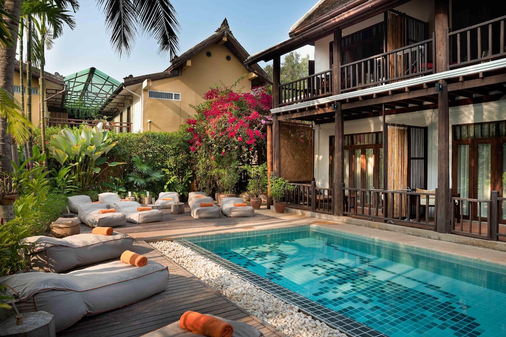 Outdoor pool with sun loungers and tropical plants at Maison Dalabua resort
