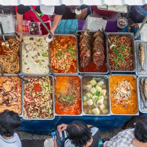 Top view of street food stall with trays of dishes and grilled fish