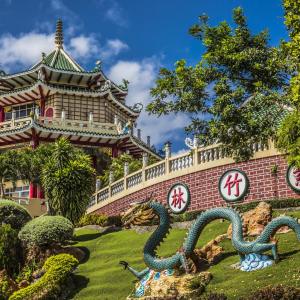 Chinese pagoda with green-tiled roof and dragon statue in landscaped garden