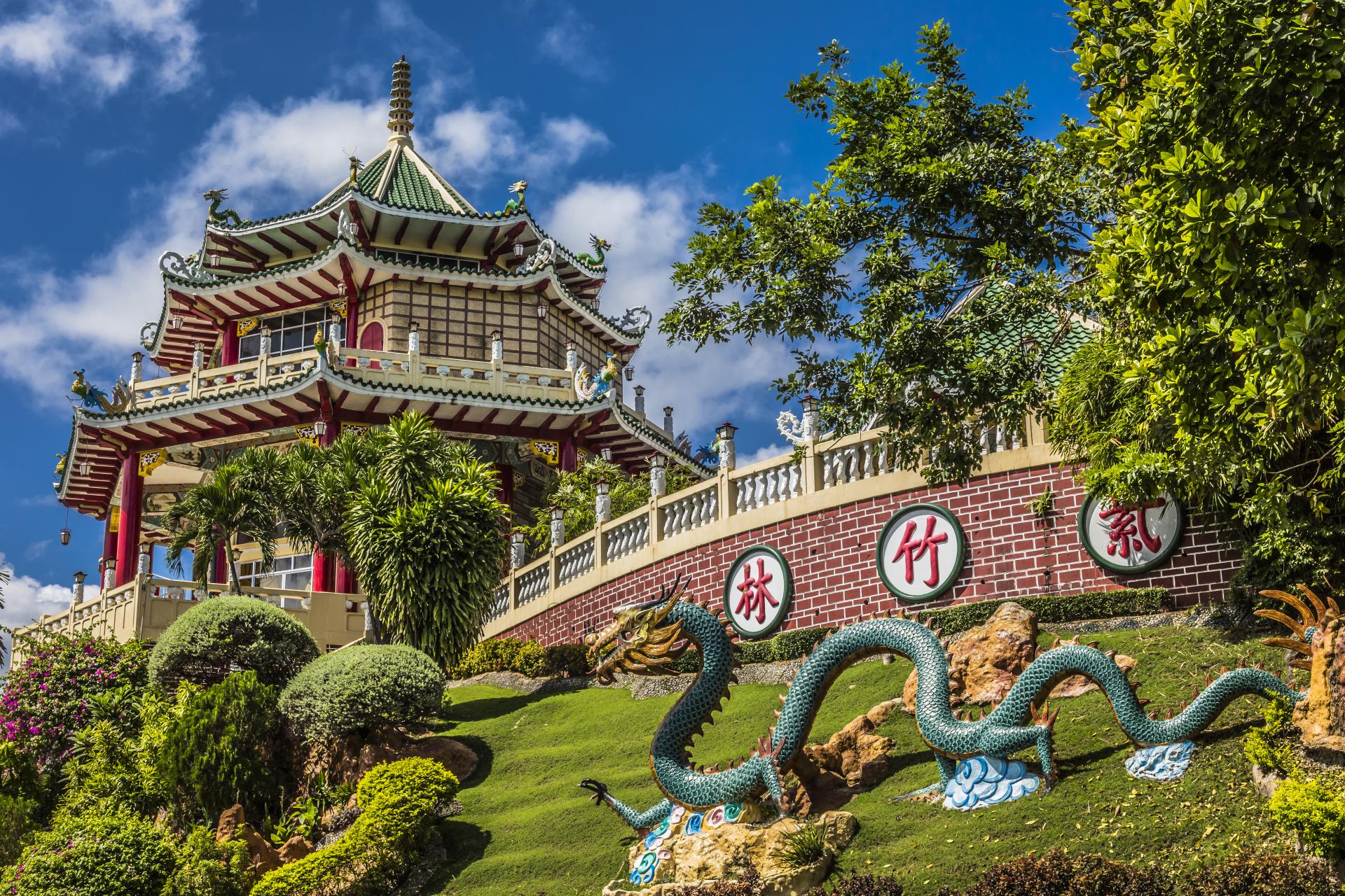 Chinese pagoda with green-tiled roof and dragon statue in landscaped garden