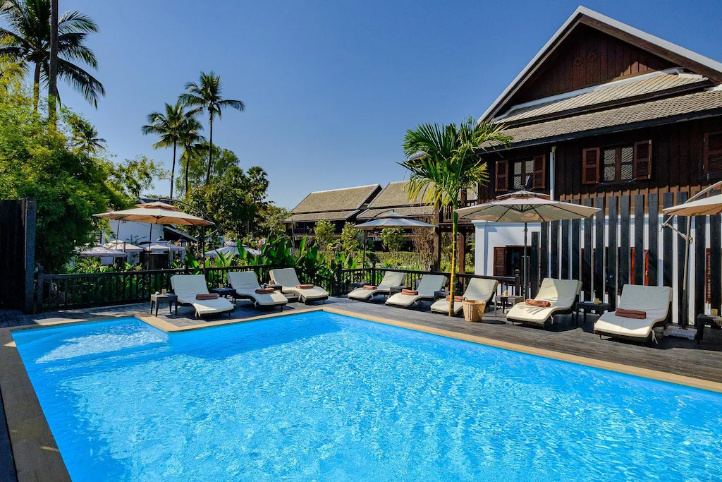 Outdoor swimming pool with sun loungers and umbrellas at Sanctuary Luang Prabang Hotel