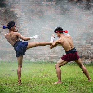 Two men practicing Muay Thai martial arts kicking and defending outside