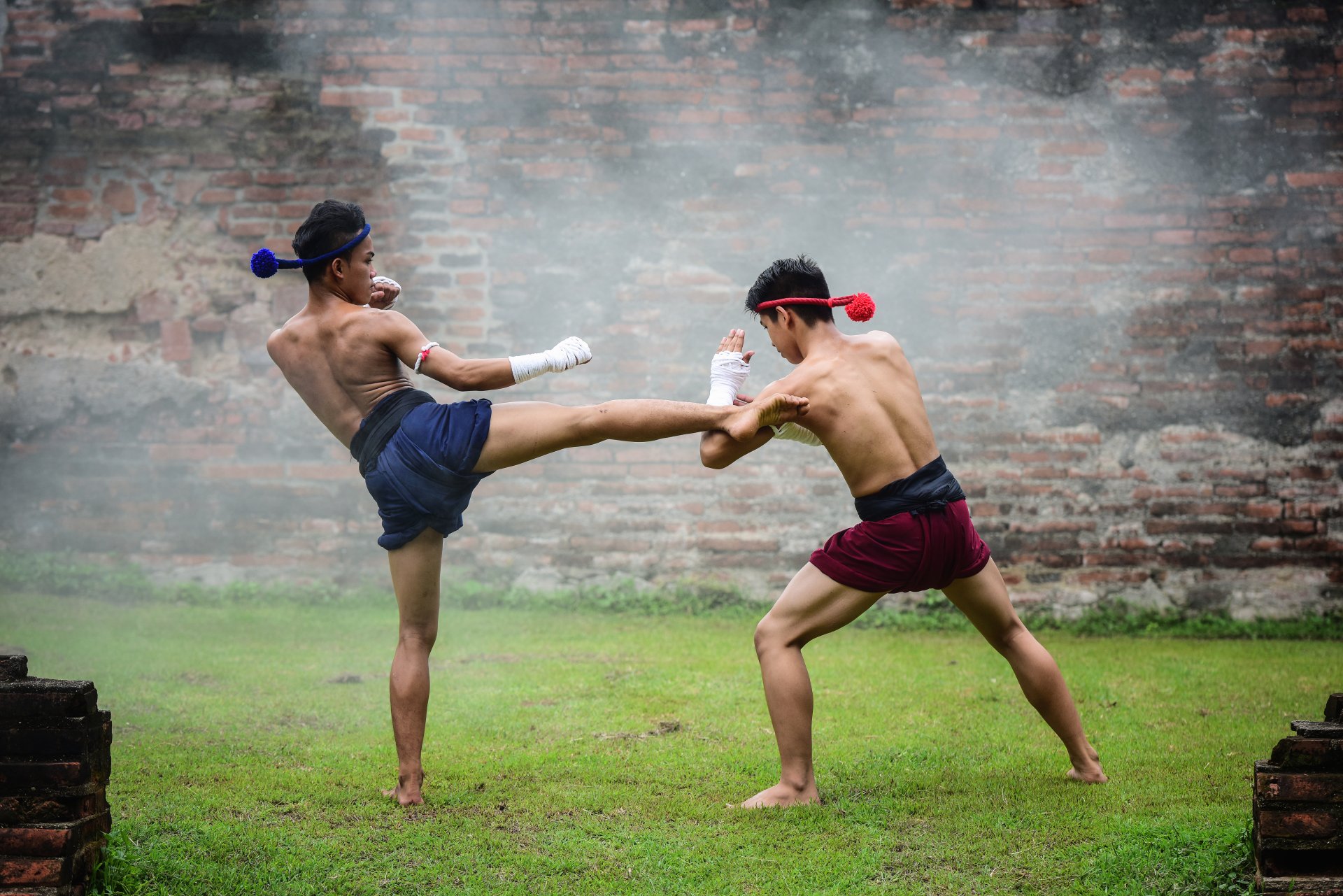 Two men practicing Muay Thai martial arts kicking and defending outside