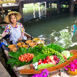 Woman selling fresh fruits and vegetables from boat at floating market