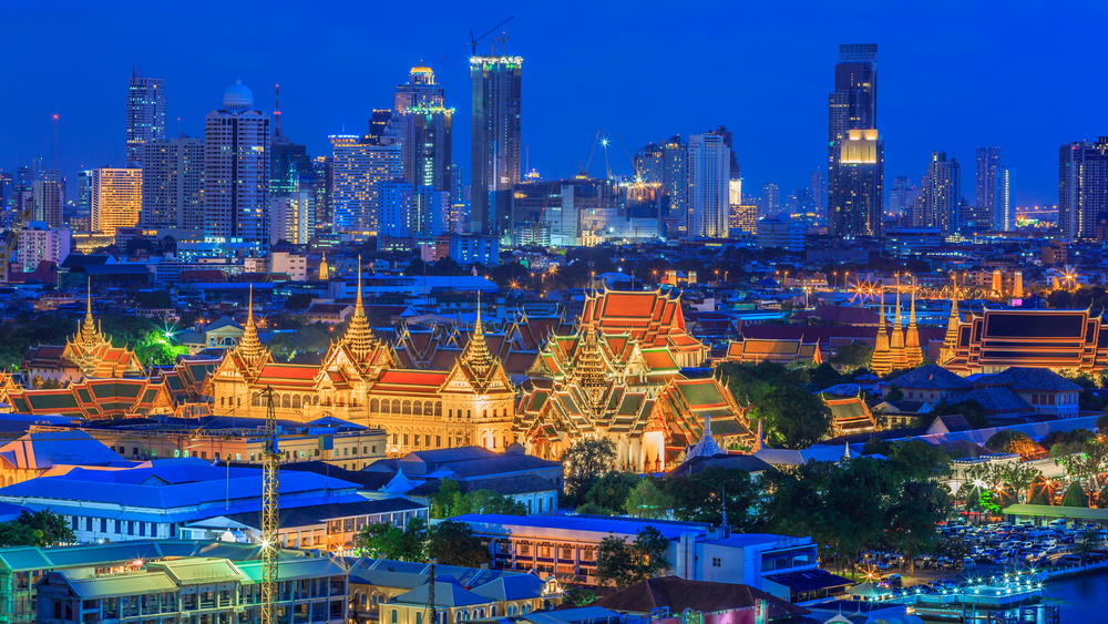 Grand Palace in Bangkok lit up at night with city skyline in background