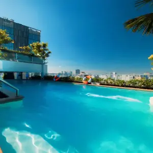 Rooftop swimming pool with greenery and city buildings in background