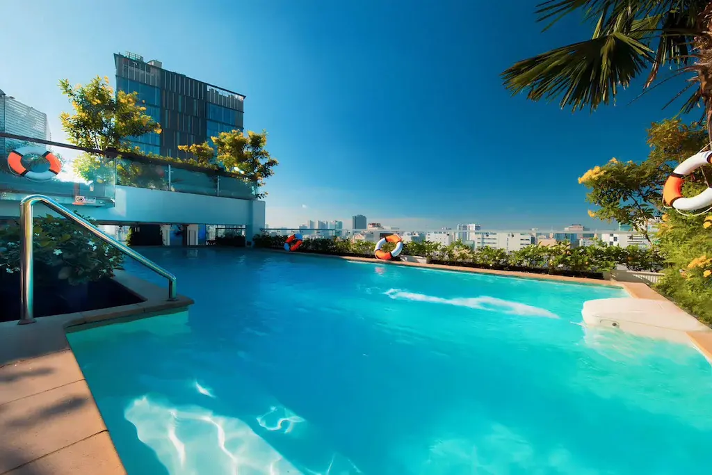 Rooftop swimming pool with greenery and city buildings in background