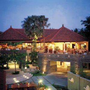 Lit Balinese boutique resort building with traditional roof and outdoor seating at dusk