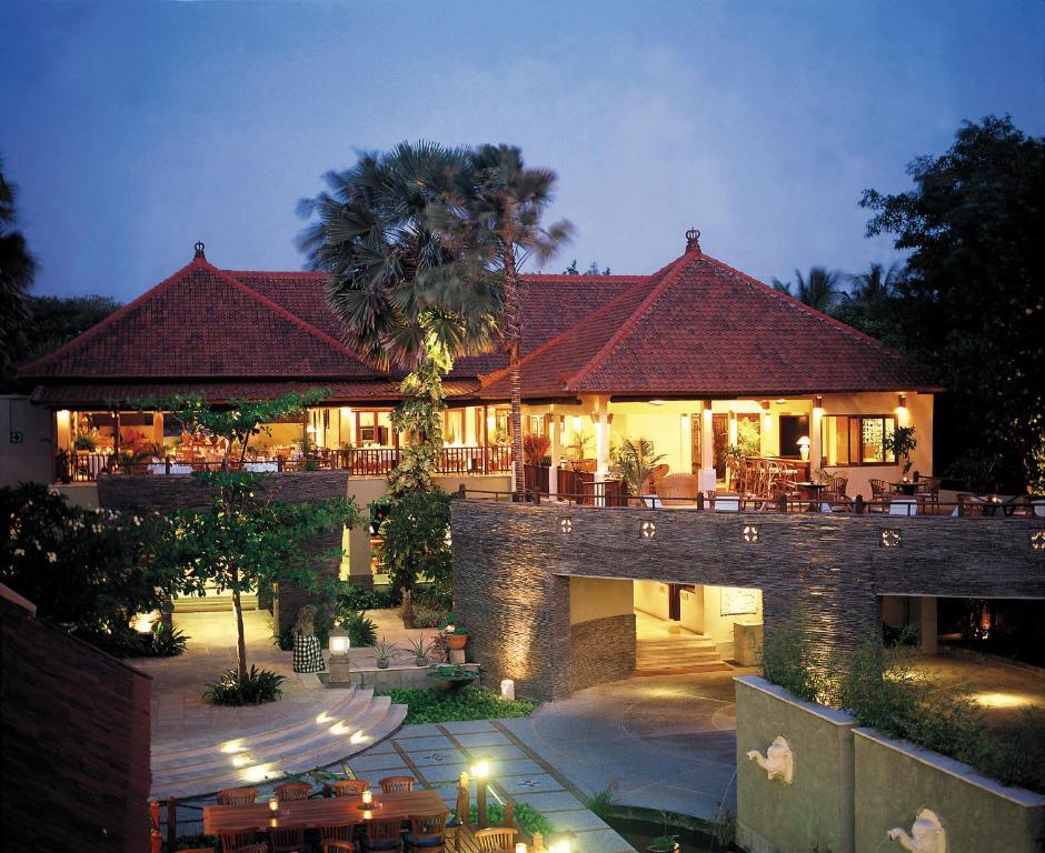 Lit Balinese boutique resort building with traditional roof and outdoor seating at dusk