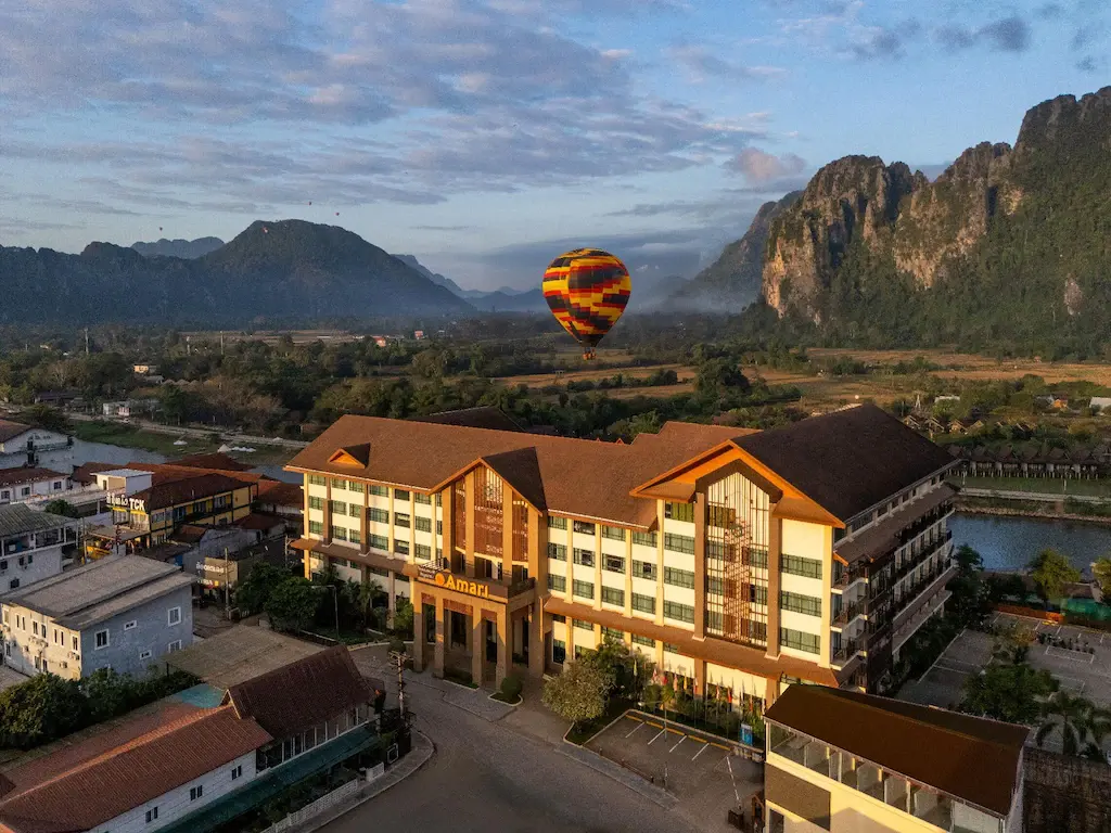 Amari Vang Vieng hotel with hot air balloon and karst mountains at sunrise
