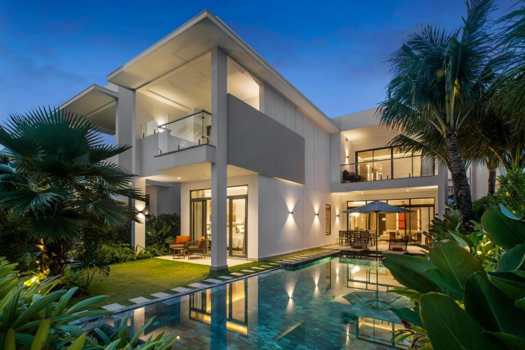 Modern villa at Angsana Ho Tram with pool and tropical garden at dusk
