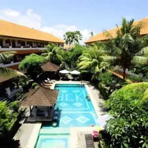 Outdoor swimming pool with tropical greenery and traditional buildings at Bakung Sari Resort & Spa