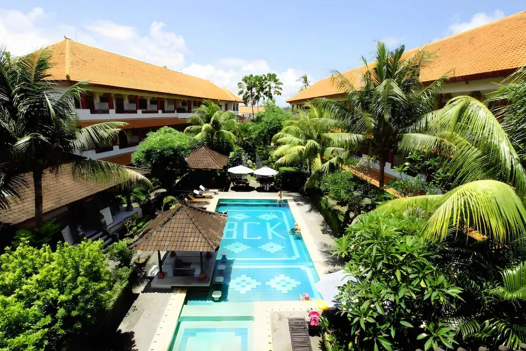 Outdoor swimming pool with tropical greenery and traditional buildings at Bakung Sari Resort & Spa