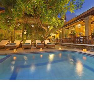 Outdoor resort pool with lounge chairs and tropical plants at dusk