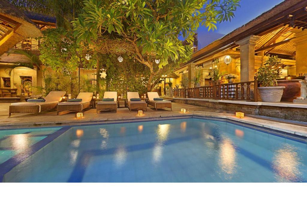 Outdoor resort pool with lounge chairs and tropical plants at dusk