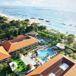Aerial view of tropical resort with swimming pool, gardens, beach and boats on sea
