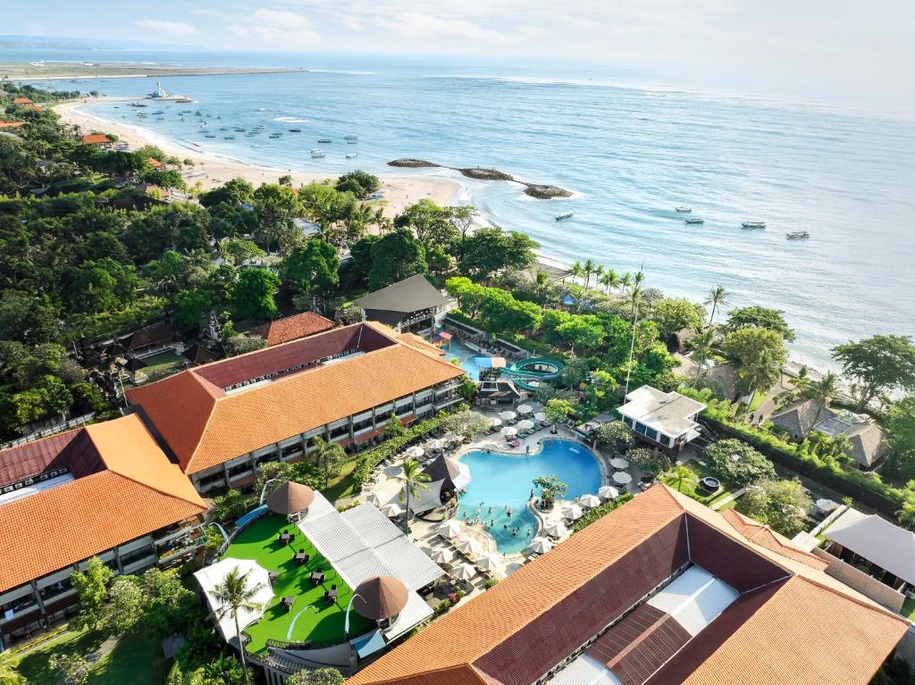 Aerial view of tropical resort with swimming pool, gardens, beach and boats on sea
