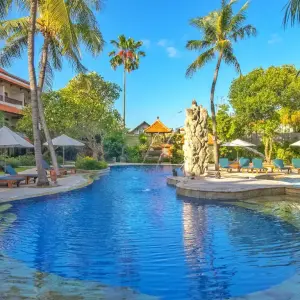 Clear blue swimming pool at tropical resort with palm trees and lounge chairs