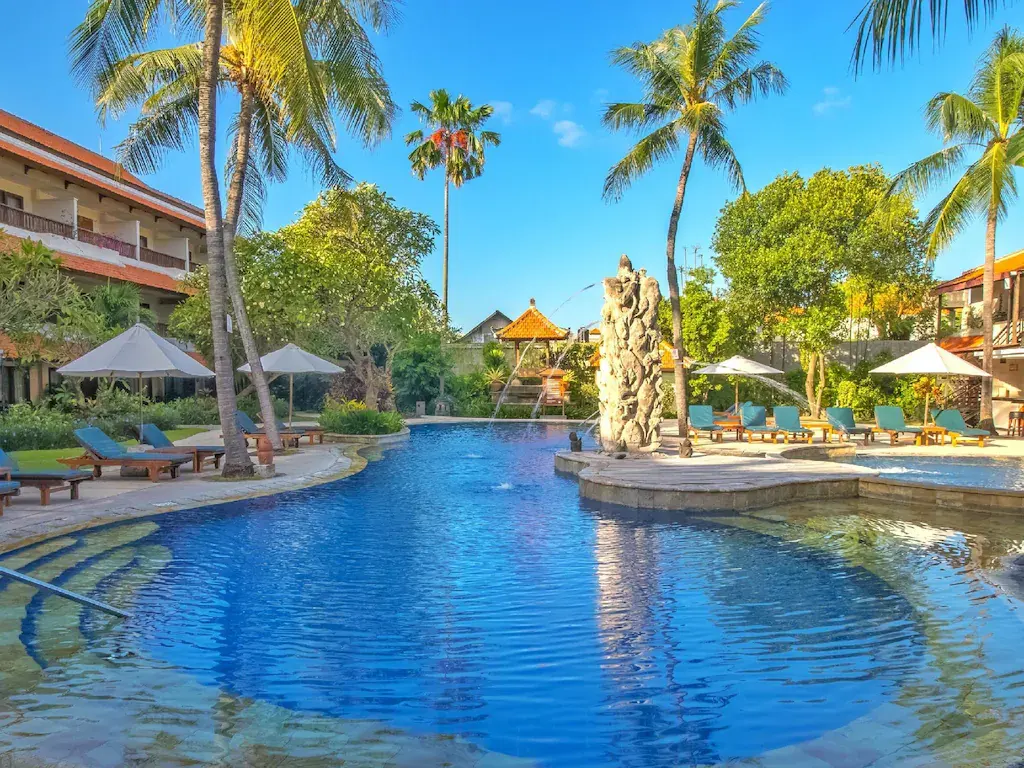 Clear blue swimming pool at tropical resort with palm trees and lounge chairs