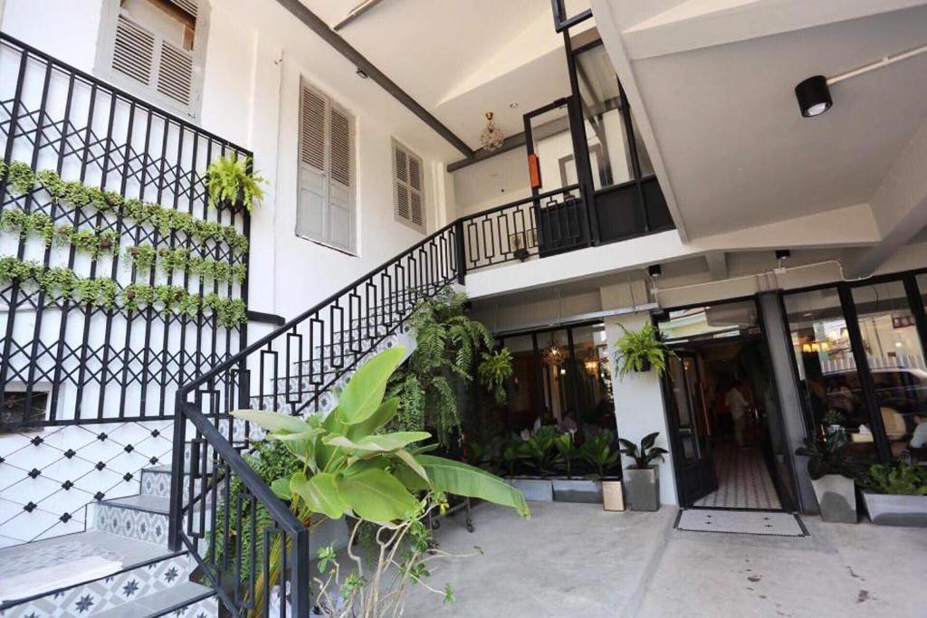 Bloom Hotel and Cafe courtyard with stairs, black railings, tiled wall, and green plants.