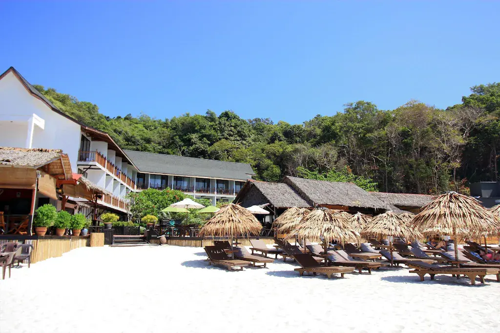 Beachfront of BuBu Resort with lounge chairs and thatched umbrellas on white sand