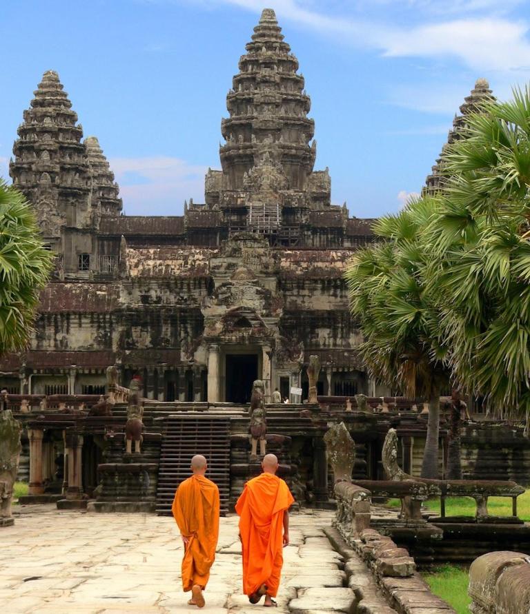Two Buddhist monks walking toward Angkor Wat temple in Cambodia