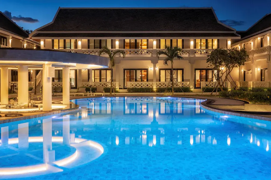 Choasis Hotel outdoor swimming pool lit at dusk with hotel building in background