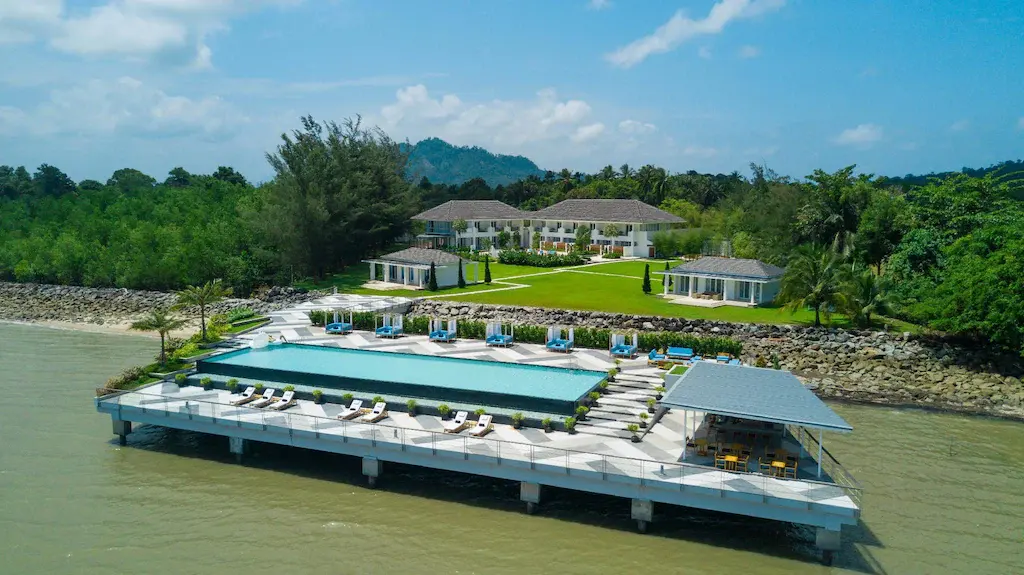 Aerial view of Cove 55 resort with infinity pool and surrounding gardens by the water