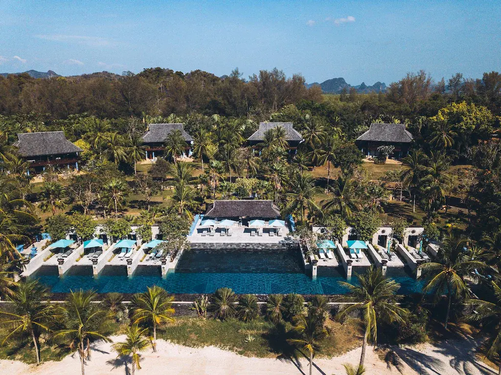 Aerial view of Four Seasons Resort Langkawi beachfront pool, palm trees, and villas.