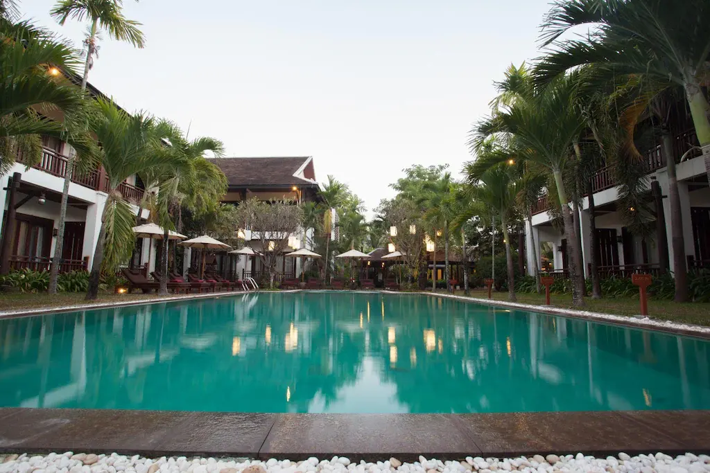 Swimming pool with palm trees and resort buildings at Green Park Boutique Hotel.