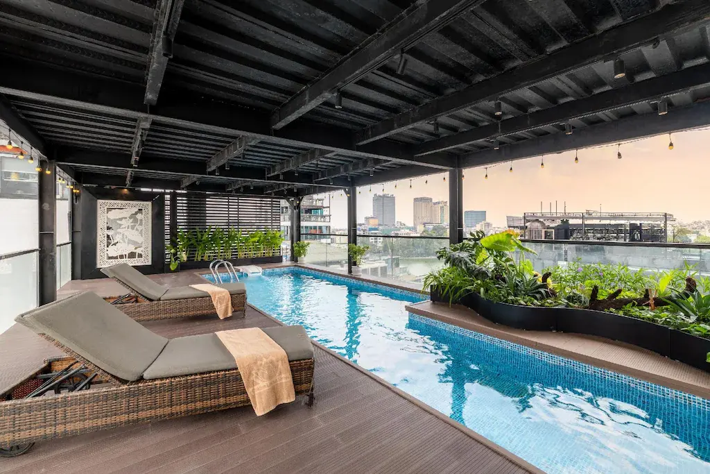 Covered rooftop swimming pool with lounge chairs and city buildings in background