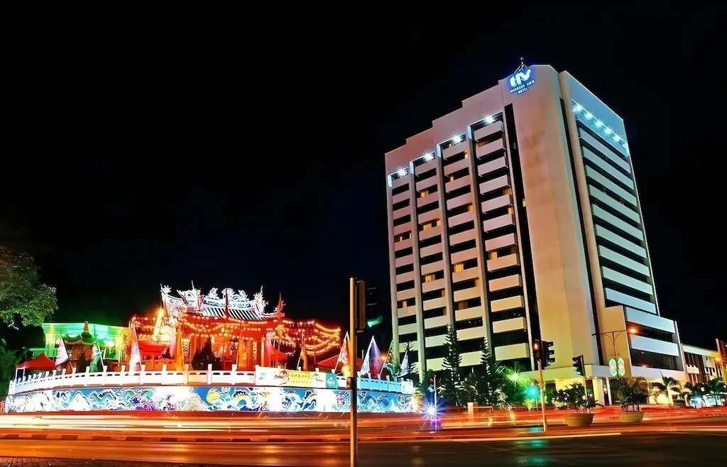 Night view of Harbour View Hotel next to brightly illuminated colorful temple with traffic light trails