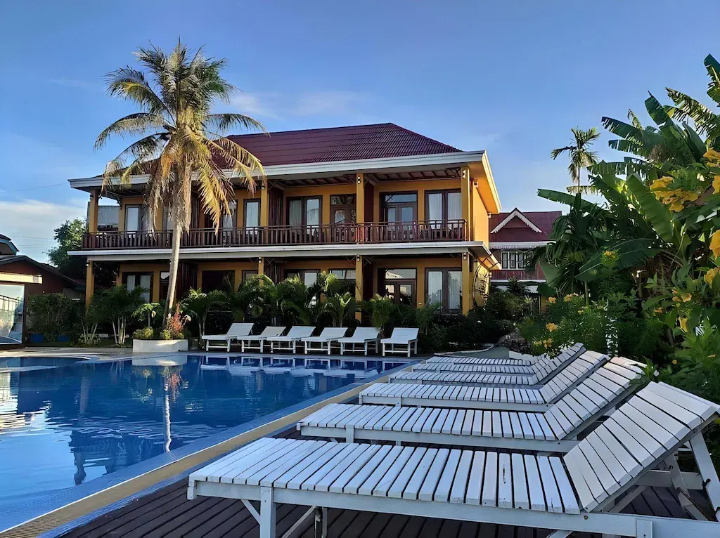 Poolside with white loungers and palm trees at Hotel Golden Dondet in daylight